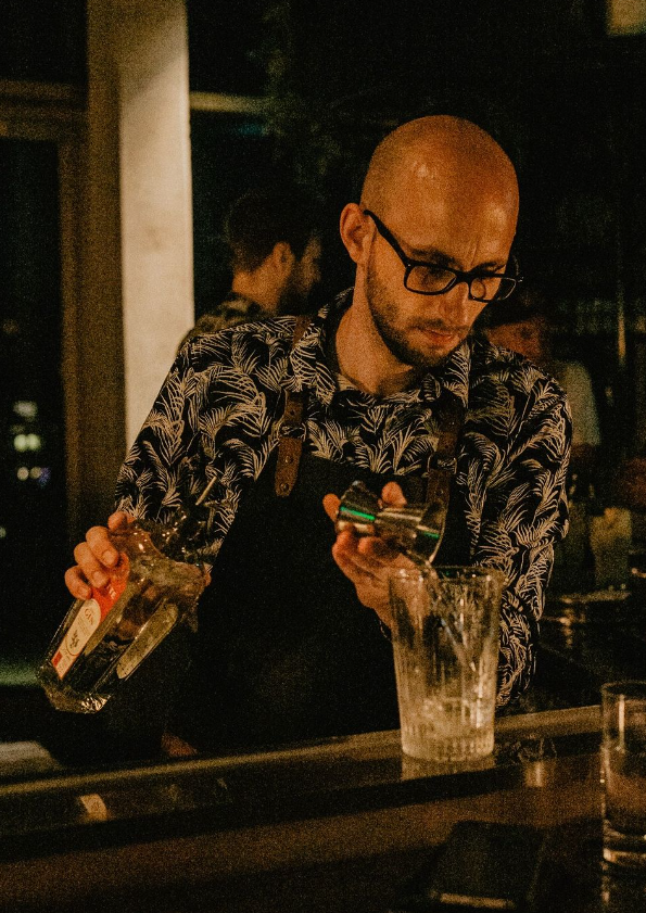 A bartender is pouring liquor into a cocktail glass at the Monkey Bar Cologne